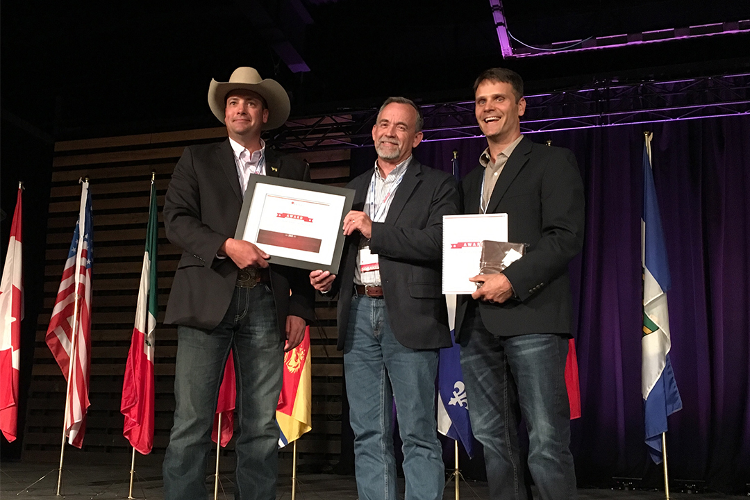 Ryan Beierbach, BCRC chair (left), and Dr. Steve Hendrick, co-presenter and veterinarian at Coaldale Veterinary Clinic (right), present Dr. John Campbell with the 2019 Canadian Beef Industry Award for Outstanding Research and Innovation.